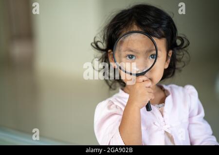 Adorable petite fille jouant avec une loupe Banque D'Images