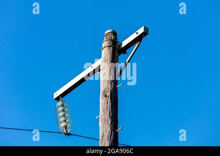 Photographie d'un poste téléphonique en bois et de câbles contre un ciel bleu Banque D'Images