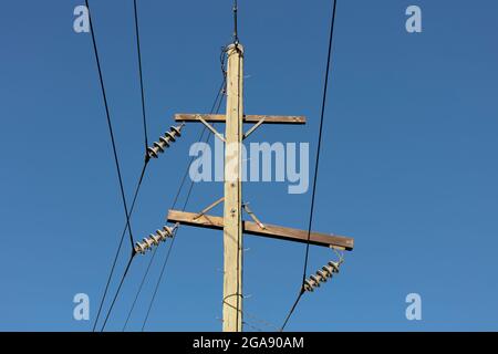 Photographie d'un poste téléphonique en bois et de câbles contre un ciel bleu Banque D'Images