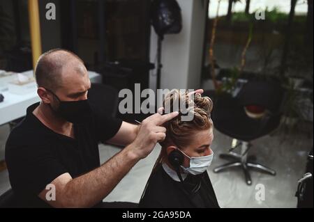 Coiffeur professionnel de sexe masculin teint les cheveux de son client dans le salon. Coupe-cheveux pour couper les cheveux. Banque D'Images
