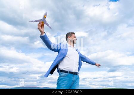 homme heureux confiant homme d'affaires en veste tenir jouet avion sur fond de ciel, succès d'affaires Banque D'Images