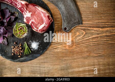 Séchez le steak de bœuf Tomahawk vieilli cru avec des ingrédients pour le gril Banque D'Images