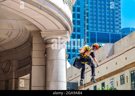 Les femmes de ménage se sont enorimées d'un gratte-ciel de verre contemporain qui nettoie les fenêtres, Canary Wharf Londres, Royaume-Uni Banque D'Images