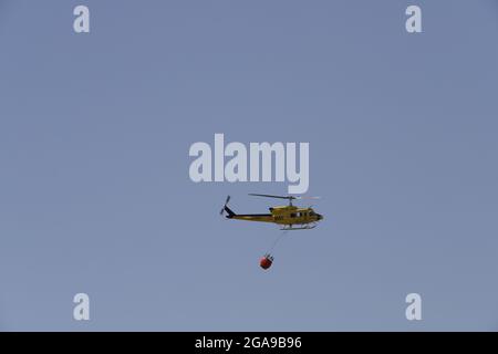 Un hélicoptère de secours en cas d'incendie qui recherche et prend de l'eau pour éteindre un incendie dans les montagnes d'Almanzora, Almeria, Espagne Banque D'Images