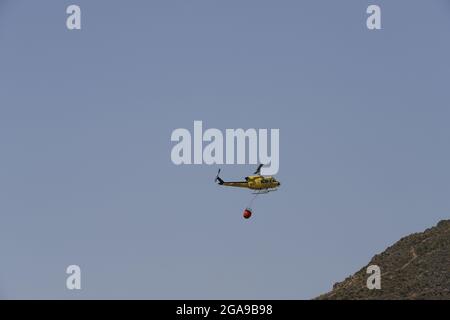 Un hélicoptère de secours en cas d'incendie qui recherche et prend de l'eau pour éteindre un incendie dans les montagnes d'Almanzora, Almeria, Espagne Banque D'Images