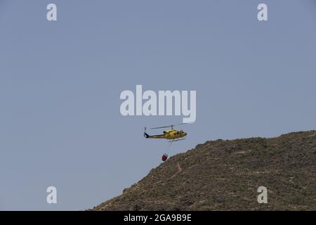 Un hélicoptère de secours en cas d'incendie qui recherche et prend de l'eau pour éteindre un incendie dans les montagnes d'Almanzora, Almeria, Espagne Banque D'Images