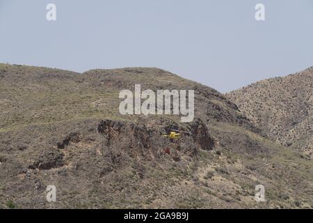 Un hélicoptère de secours en cas d'incendie qui recherche et prend de l'eau pour éteindre un incendie dans les montagnes d'Almanzora, Almeria, Espagne Banque D'Images