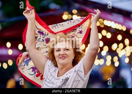 Une femme heureuse âgée marche à l'extérieur avec un foulard dans les mains. Banque D'Images