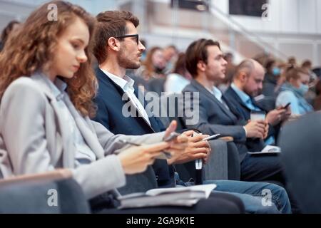 les jeunes gens d'affaires utilisent leur smartphone pendant l'atelier. Banque D'Images