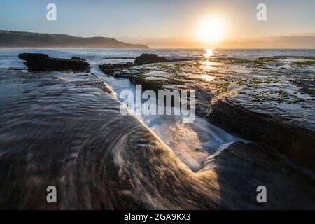 guayer dans les rochers au lever du soleil sur la plage Banque D'Images