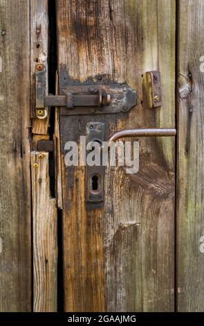 détails de l'ancienne météo belle porte de grange texturée en bois avec fer, serrure rouillée et poignée de porte Banque D'Images