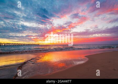 Vagues s'écrasant sur la plage de Port Noarlunga avec jetée et coucher de soleil spectaculaire sur le fond Banque D'Images