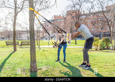 Couple de forme physique faisant des bras exercice avec trx sangles de forme physique dans le parc Banque D'Images