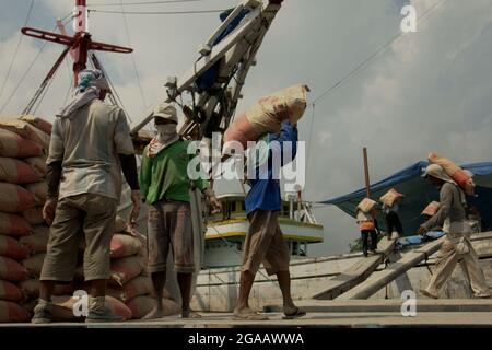 Les travailleurs transportent des sacs de ciment d'un camion sur un navire phinisi au port traditionnel de Sunda Kelapa à Penjaringan, dans le nord de Jakarta, à Jakarta, en Indonésie. Banque D'Images