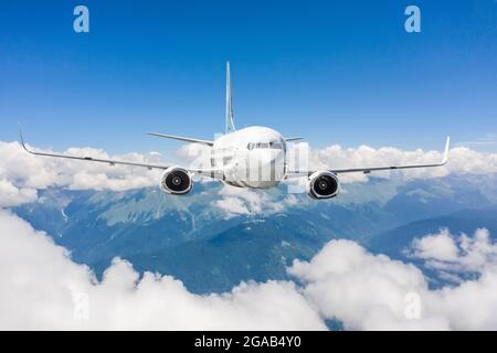 L'avion vole au-dessus des nuages et des chaînes de montagnes Banque D'Images