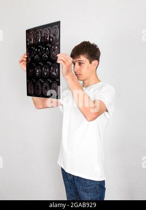 Jeune homme tient l'acquisition de rayons X sur l'arrière-plan du mur blanc Banque D'Images