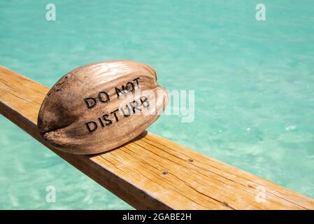 Noix de coco avec ne pas déranger mots lettre gravée de la couleur de l'océan plage et vert transparent eau à l'île de Maldive. Banque D'Images