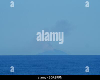 Ciel bleu et mer avec des panaches de fumée s'élevant d'une petite île, côte de Nouvelle-Galles du Sud Australie Banque D'Images