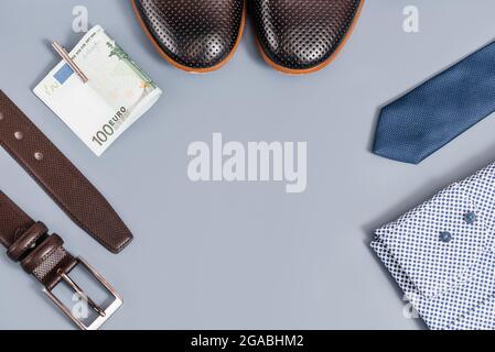 Vêtements et accessoires pour hommes.T-shirt cravate et chaussures, argent ceinture. Sur fond bleu, espace copie.vue du dessus Banque D'Images