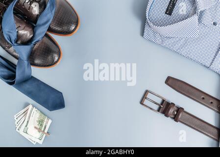 Vêtements et accessoires pour hommes.T-shirt cravate et chaussures, argent ceinture. Sur fond bleu, espace copie.vue du dessus Banque D'Images