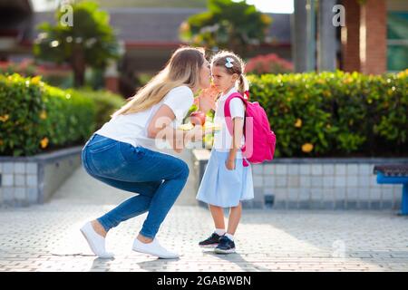 Mère et enfants après l'école. Une jeune mère prend des enfants après des leçons de maternelle ou d'école maternelle. Prenez les élèves. Garçon et fille courant Banque D'Images