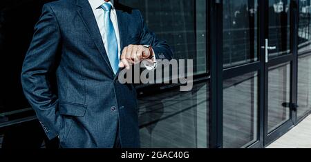 une bannière avec l'image d'une silhouette masculine dans un costume d'affaires regarde l'horloge vérifie l'heure. Banque D'Images