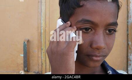 Gros plan d'un garçon rural parlant au téléphone, Inde. Banque D'Images