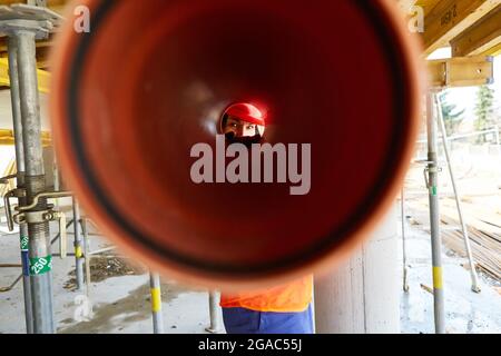 CRAFTSMAN regarde à travers un tuyau d'évacuation lors de l'installation dans la coquille d'un chantier de construction Banque D'Images