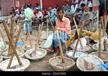 DHAKA, BANGLADESH - JUILLET 28 : les travailleurs sont assis sur le trottoir avec des paniers et des crapules à chercher du travail, après que le gouvernement a annoncé le verrouillage pour prévenir les cas positifs par Covid-19 en raison d'une augmentation des infections le 28 juillet 2021 à Dhaka, au Bangladesh. Crédit : Habibur Rahman/Groupe Eyepix/accès photo Banque D'Images