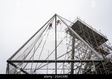 Des experts descendent en rappel du Snowdon Aviary classé Grade II au zoo de Londres ZSL à Regent's Park, Londres, pour retirer le premier des 200 panneaux en maille d'acier qui enveloppent la structure qui est restée inchangée depuis plus de 50 ans, Début du compte à rebours d'un an jusqu'à la renaissance de l'été 2022 comme nouvelle maison pour une troupe de singes colobus noirs et blancs de l'est. Date de la photo : vendredi 30 juillet 2021. Banque D'Images