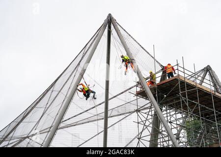 Des experts descendent en rappel du Snowdon Aviary classé Grade II au zoo de Londres ZSL à Regent's Park, Londres, pour retirer le premier des 200 panneaux en maille d'acier qui enveloppent la structure qui est restée inchangée depuis plus de 50 ans, Début du compte à rebours d'un an jusqu'à la renaissance de l'été 2022 comme nouvelle maison pour une troupe de singes colobus noirs et blancs de l'est. Date de la photo : vendredi 30 juillet 2021. Banque D'Images