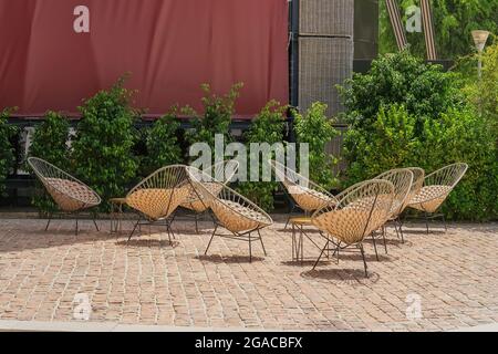 Terrasse avec mobilier moderne en osier confortable. Chaises en osier crème artisanales contemporaines en rotin naturel dans un café vide. Banque D'Images