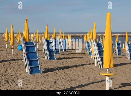 de nombreux parasols jaunes fermés et des chaises longues sur la plage déserte sans personnes Banque D'Images