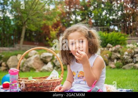 Petite fille ayant un pique-nique dans leur jardin lors d'une chaude journée d'été Banque D'Images