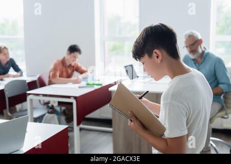 Écolier asiatique avec ordinateur portable debout dans la salle de classe Banque D'Images