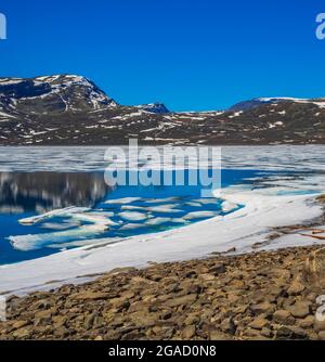 Lac turquoise gelé Vavatn panorama en été paysage et montagnes avec neige à Hemsedal Norvège. Banque D'Images