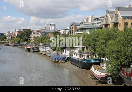 Des bateaux-maisons amarrés sur la rive nord de la Tamise à l'ouest de Kew Bridge, Londres, Royaume-Uni. Les coques reposent sur des faisceaux temporaux pour les maintenir à niveau à marée basse. Banque D'Images