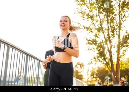 Deux jeunes femmes Happy FIT dans des vêtements de sport qui se rassemblent dans le parc public en été le matin, priorité sélective sur la première femme blonde joyeuse Banque D'Images