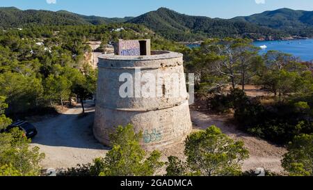 Vue aérienne de la tour ronde (Torre) de Portinatx sur la rive nord de l'île d'Ibiza en Espagne - forêts de pins et falaises rocheuses dans l'île des Baléares Banque D'Images