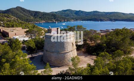 Vue aérienne de la tour ronde (Torre) de Portinatx sur la rive nord de l'île d'Ibiza en Espagne - forêts de pins et falaises rocheuses dans l'île des Baléares Banque D'Images