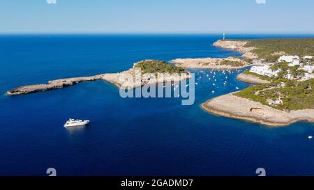 Vue aérienne de la baie de Portinatx sur la rive nord de l'île d'Ibiza en Espagne - bateaux ancrés près d'une plage de sable entourée de forêts de pins Banque D'Images