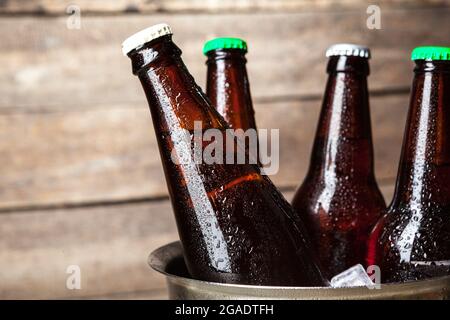 Bouteilles froides de bière dans le seau sur le fond en bois Banque D'Images