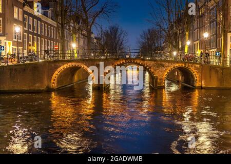 Pont avec arches, illuminé la nuit, canaux Herengracht et Leidsegracht, Amsterdam Banque D'Images