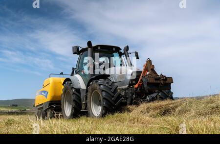 Entrepreneur équipé d'une presse à balles argentée Hurlimann et New Holland, qui fait de grosses balles carrées de foin dans un pré traditionnel des bières, à Hawes, dans le North Yorkshire, au Royaume-Uni. Banque D'Images