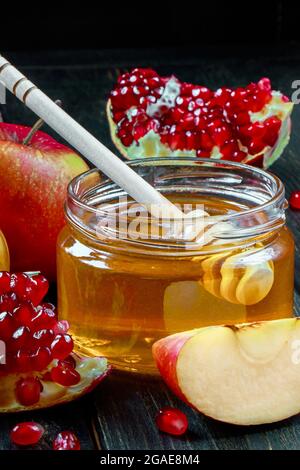 Fête religieuse juive traditionnelle Rosh Hashanah. Pommes, grenades et miel sur fond de bois foncé. Photo verticale. Banque D'Images