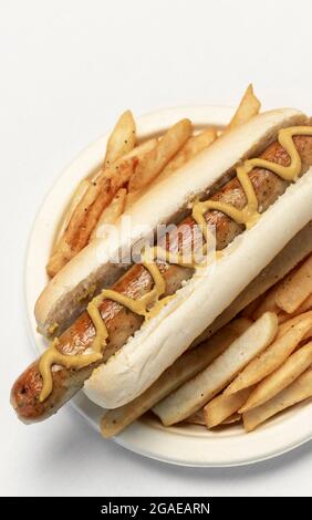 hot dog allemand avec frites et moutarde sur fond blanc Banque D'Images