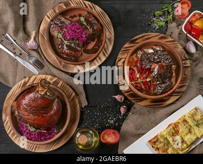 Jarret de porc cuit au four, ventre de porc, côtes de veau avec sauces et légumes Banque D'Images