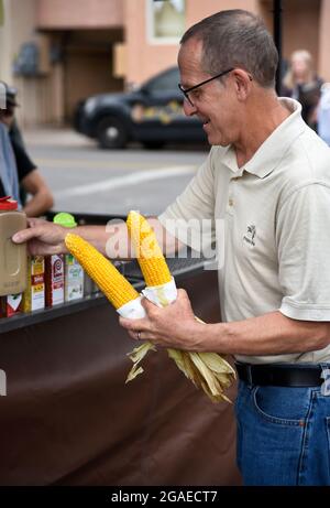 Un homme achète deux épis de maïs torréfié sur le rafle d'un stand de restauration lors d'un festival en plein air à Santa Fe, Nouveau-Mexique. Banque D'Images