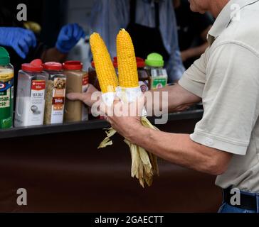 Un homme achète deux épis de maïs torréfié sur le rafle d'un stand de restauration lors d'un festival en plein air à Santa Fe, Nouveau-Mexique. Banque D'Images