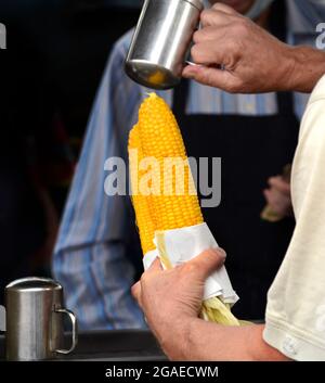 Un homme achète deux épis de maïs torréfié sur le rafle d'un stand de restauration lors d'un festival en plein air à Santa Fe, Nouveau-Mexique. Banque D'Images